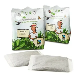 To pakker puro fairtrade kaffe med illustrasjoner av mennesker og natur på etikettene, og to løse teposer foran.