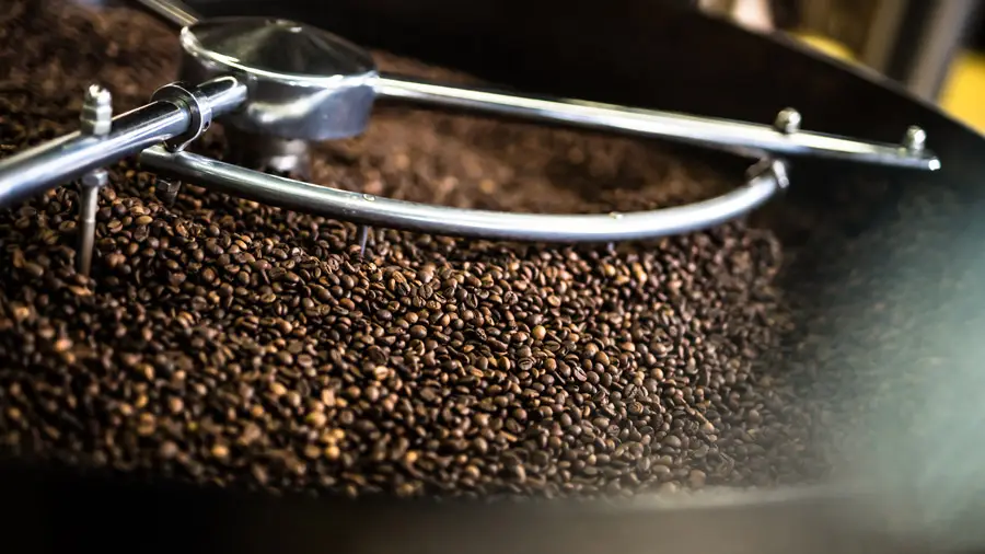 Brent kaffebønner blir rørt av en mekanisk omrører i en kommersiell brennemaskin på Om Kaffebryggeriet.