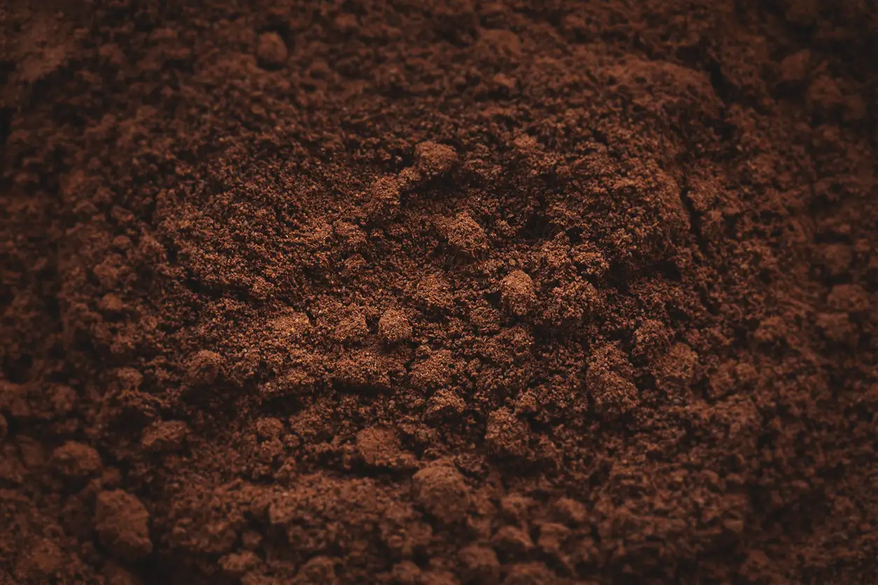 Nærbilde av fyldig, mørkebrun kaffegrut med et strukturert, granulært utseende, ideelt for gjenbruk av kaffegrut.
