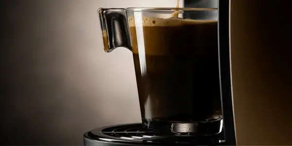 Espresso fra en Franke Spectra X-XL kaffemaskin i en glasskopp på mørk bakgrunn.